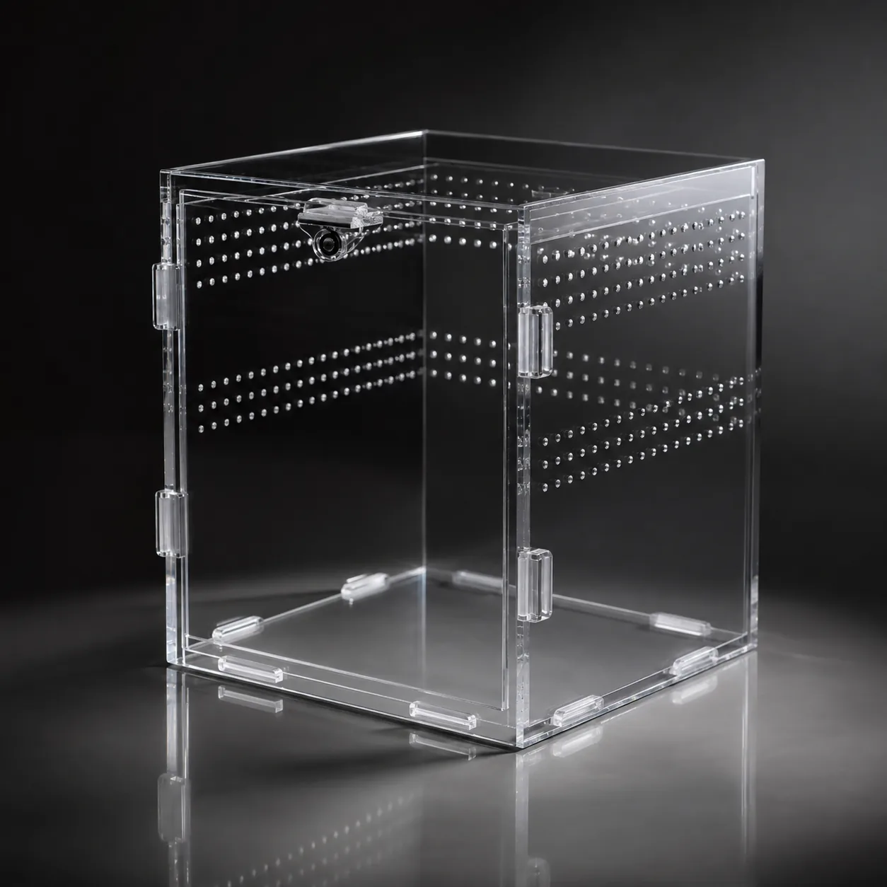 An empty crystal-clear acrylic enclosure on a dark background, its optically clear cast-acrylic panels and ventilation holes catching the light